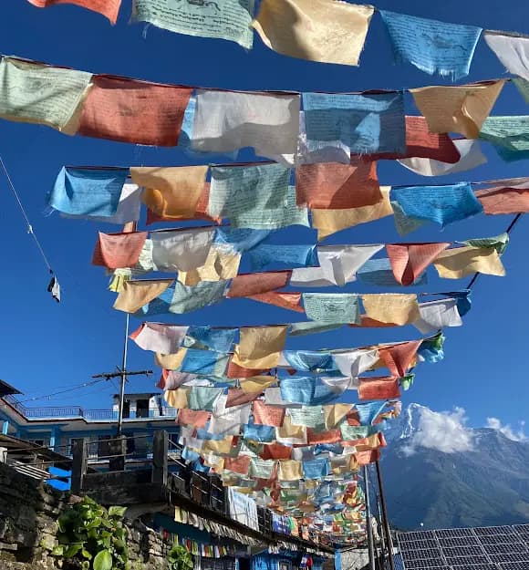 Colorful Tibetan prayer flags fluttering against a Himalayan mountain backdrop in Nepal