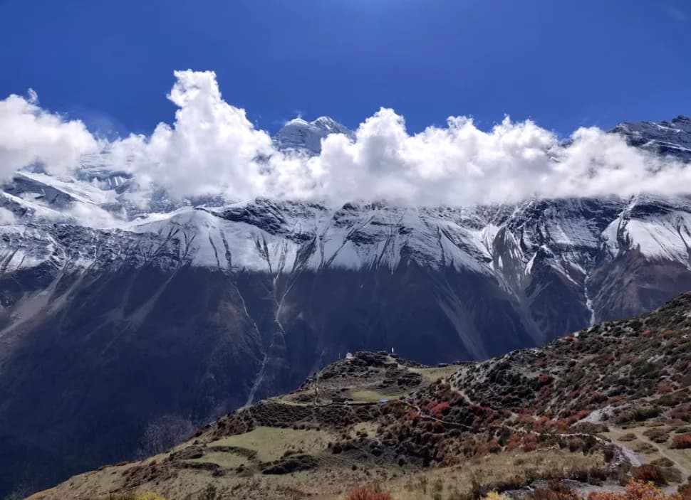 Trekkers crossing Thorong La Pass at 5,416m on the Annapurna Circuit with prayer flags and mountain views